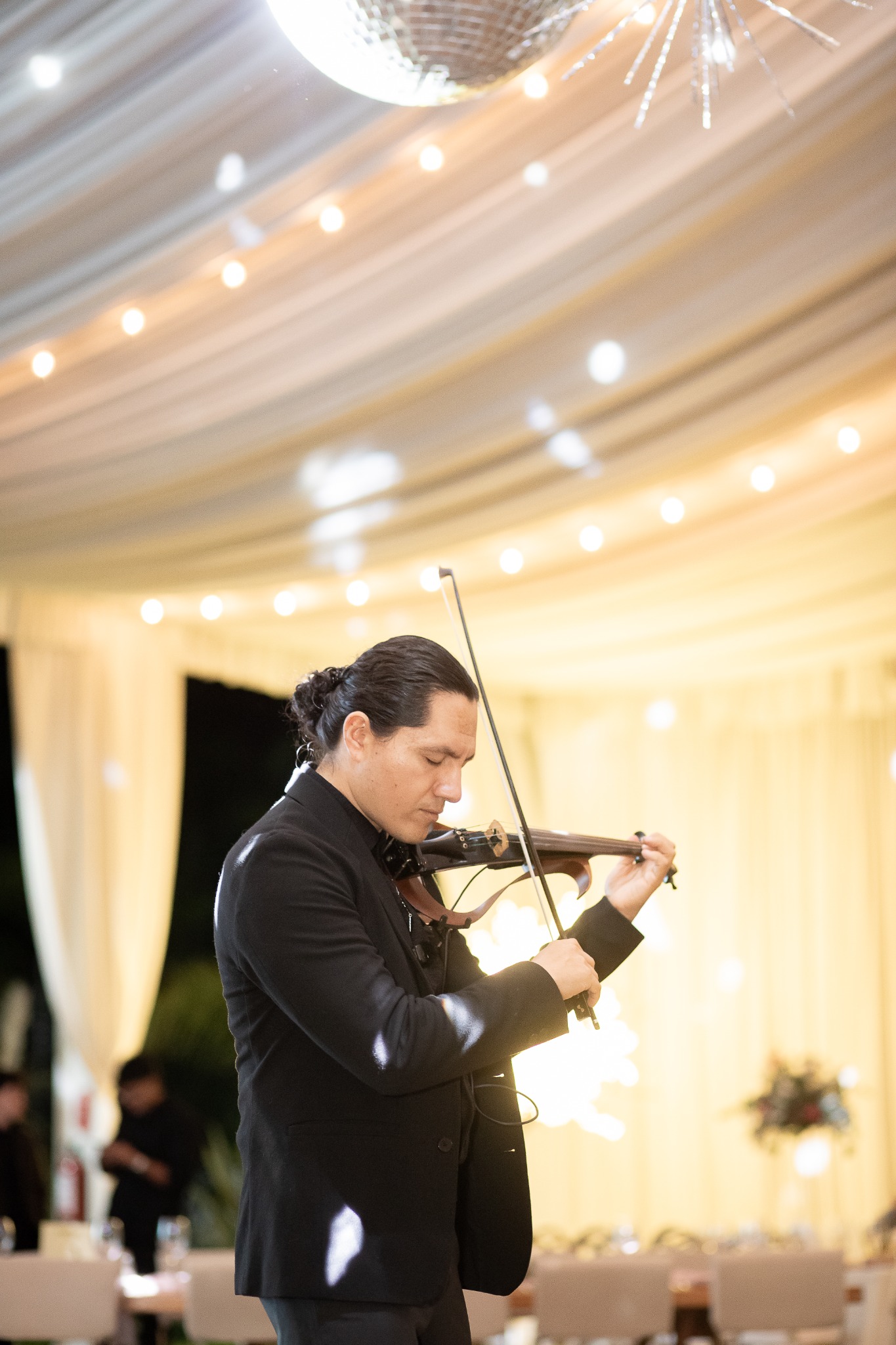 Miguel Fajardo interpretando el violín bajo las luces cálidas de una celebración